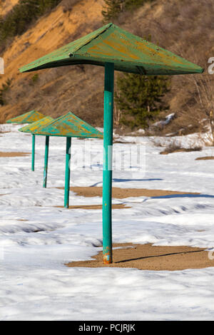 Parasols rouillée abandonnée sur une plage couverte de neige. Banque D'Images