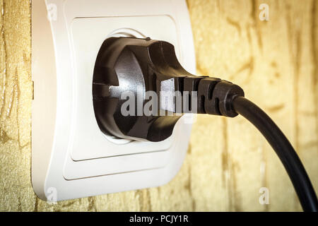 Bouchon noir électrique dans une prise d'alimentation blanc close-up. Banque D'Images