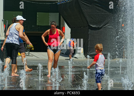 Les gens gardent leur sang froid dans l'eau des fontaines à Montréal dans la canicule 2018 Banque D'Images
