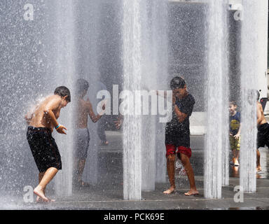 Rafraîchir les enfants jouant dans l'eau des fontaines dans la rue Jeanne Mance Montréal dans le quartier des divertissements. Prises au cours de la canicule de 2108. Banque D'Images