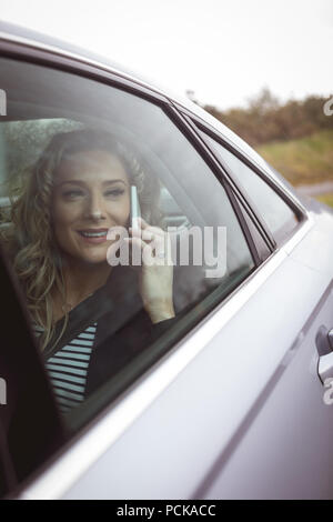 Businesswoman talking on the phone dans le siège arrière de la voiture Banque D'Images
