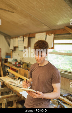 Male carpenter using digital tablet in workshop Banque D'Images