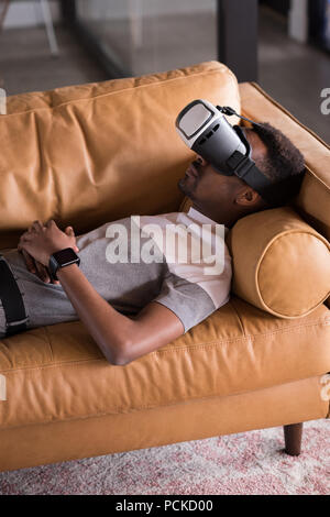 Rencontrez l'homme casque VR couchée sur canapé Banque D'Images