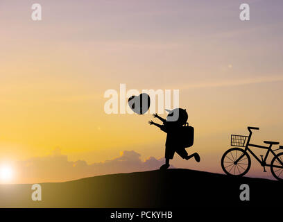 Silhouette les enfants jouent avec des ballons en forme de coeur coucher du soleil Banque D'Images