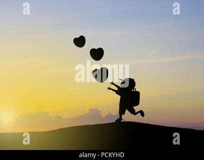 Silhouette les enfants jouent avec des ballons en forme de coeur coucher du soleil Banque D'Images