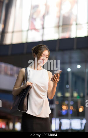 Cheerful young Chinese businesswoman using smart phone Banque D'Images