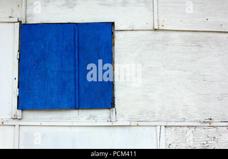 Volets fermés peintes en bleu sur un mur blanc extérieur en bois Banque D'Images