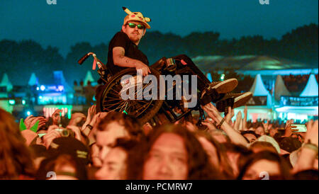 02 août 2018, l'Allemagne, le Wacken : un utilisateur de fauteuil roulant se fait par les mains des fans lors du concert du groupe britannique Judas Priest. Selon les organisateurs, le plus grand festival de heavy metal commence avec 75 000 visiteurs. Photo : Axel Heimken/dpa Banque D'Images