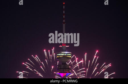 02 août 2018, l'Allemagne, Munich : le ciel derrière la tour olympique est bien éclairée par des feux d'artifice dans une nuance rose. L'artifice ont été allumé pendant le Festival d'été de Impark au Parc olympique. Photo : Lino Mirgeler/dpa Banque D'Images