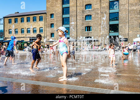 Les familles et les enfants se rafraîchissent dans les fontaines de Granary Square tandis que les températures montent, King's Cross, Londres, Royaume-Uni Banque D'Images