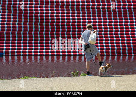 Hyde Park. Londres. UK, 3 août 2018 - Une femme marchant avec son chien devant TheÊLondon Mastaba - 20 mètres de haut de la sculpture flottant sur le lac Serpentine de Londres à Hyde Park sur une autre journée très chaude dans la capitale. D'après le Met Office la canicule est d'continue au Royaume-Uni et dans certaines parties de l'Europe dans les prochains jours avec des températures record prévu. Credit : Dinendra Haria/Alamy Live News Banque D'Images