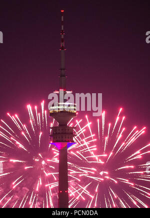 02 août 2018, Munich : le ciel derrière la tour olympique est bien éclairée par des feux d'artifice dans une nuance rose. L'artifice ont été allumé pendant le Festival d'été de Impark au Parc olympique. Photo : Lino Mirgeler/dpa Banque D'Images