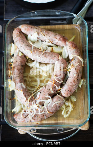 Saucisse blanche cuite au four avec les oignons dans le plat allant au four Banque D'Images