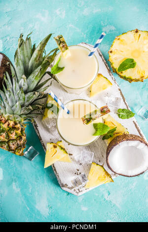 Boisson d'été rafraîchissante, de pina colada cocktail, sur un fond bleu clair, avec des morceaux d'ananas, noix de coco, de glace et de feuilles de menthe, copy space Banque D'Images
