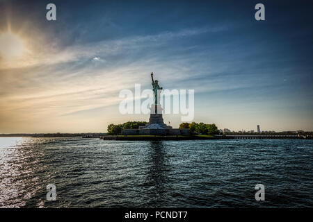 La Statue de la Liberté à New York avec le soleil couchant derrière elle. Banque D'Images