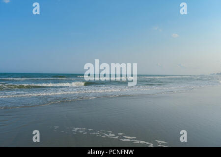 Une fin d'après-midi à pied à la plage de myrte révèle le brillant soleil voilé sur l'eau. Hôtels line la ligne de rivage au loin. Banque D'Images