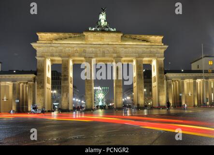 Les voitures et les gens qui passent par la porte de Brandebourg sur une breezy nuit Banque D'Images