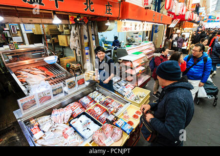 Kuromon Ichiba, marché alimentaire à Osaka. Décrochage du poisson poisson monger avec potions, overhead view, assistant parlant à client, de flou. Arcade occupé. Banque D'Images