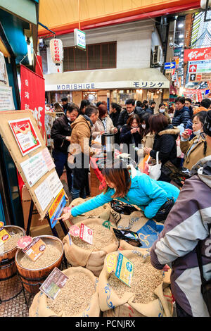 Kuromon Ichiba, marché alimentaire à Osaka. Vente de décrochage avec contre des grains de café non torréfiés offrent des échantillons de café. Très encombré et occupé avec les gens. Banque D'Images