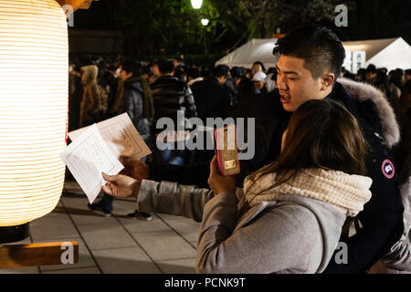 Shogatsu, nouvelle année, Nishisnomiya culte, le Japon. Couple japonais à minuit prendre photo de omikuji fortune à côté de papier la lumière des lanternes chochin. Banque D'Images