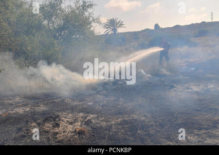 Pompiers lutter contre un incendie causé par des bombes qui ont été transportés de cerf-volant de Gaza avec un chiffon imbibé d'essence allumé, à mis le feu à un champs d'Israël Banque D'Images