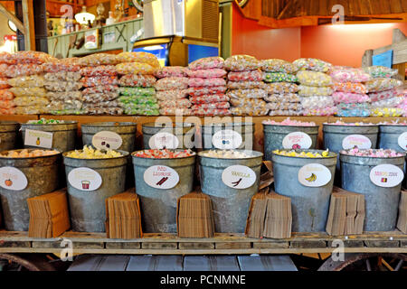 Taffy d'eau salée à vendre avec des morceaux emballés individuellement remplissant des seaux d'étain que les gens mettent dans des sacs bruns et paient au poids. Banque D'Images