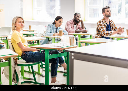 Les jeunes étudiants assis en classe pendant la leçon Banque D'Images