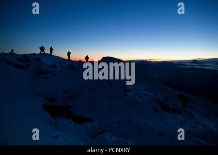 Alpinistes sur le Benediktenwand en hiver au lever du soleil, Alpes bavaroises, Upper Bavaria, Bavaria, Germany Banque D'Images