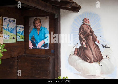 Autriche, Tyrol, Aurach, poster avec chanteur autrichien Hansi Hinterseer et peinture murale représentant Saint François d'assise Banque D'Images