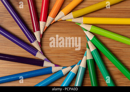 Une macro shot de crayons de couleur dans une spirale tourbillon sur une table en bambou. Suivez les couleurs de l'ombre et la couleur d'un motif de couleur standard Banque D'Images