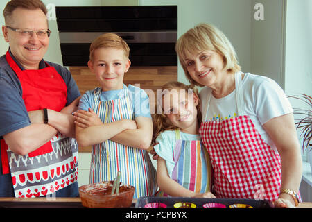 Portrait d'heureux grands-parents de s'amuser avec leurs petits-enfants la préparation de muffins au chocolat dans la cuisine moderne Banque D'Images