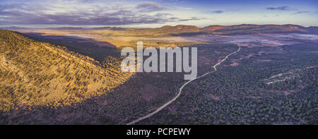 Paysage panoramique de l'antenne de gravier en passant par les collines de la chaîne des Flinders et la végétation indigène au coucher du soleil dans le sud de l'Australie Banque D'Images