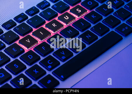 Virus écrit en rouge sur un clavier d'ordinateur portable rétroéclairé close-up avec focus sélectif dans un environnement de lumière bleu Banque D'Images