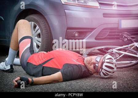 Cycliste couché sur la route après un accident impliquant une voiture et un vélo Banque D'Images