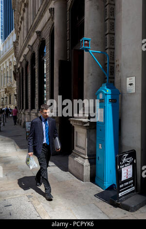 Un homme passe devant l'une des dernières zones de signal de la police sur Threadneedle Street dans la ville de Londres, la capitale historique du quartier financier, le 2 août 2018, à Londres, en Angleterre. La zone de Police est une cabine téléphonique publique ou callbox pour l'utilisation de membres de la police, ou des membres du public à communiquer avec la police. Il a été introduit aux États-Unis en 1877 et a été utilisé au Royaume-Uni tout au long du xxe siècle, depuis le début des années 20. Banque D'Images