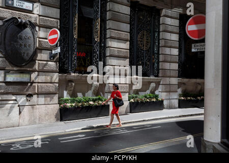 Une dame dans une robe rouge marche sur la rue Finch, un étroit couloir de l'époque médiévale dans la ville de Londres, la capitale historique du quartier financier, le 2 août 2018, à Londres, en Angleterre. Banque D'Images