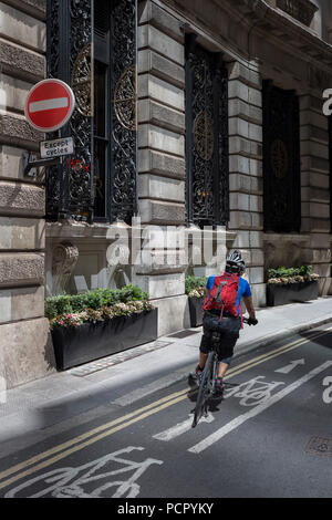 Un cycliste se tourne sur une voie cyclable sur la rue Finch, un étroit couloir de l'époque médiévale dans la ville de Londres, la capitale historique du quartier financier, le 2 août 2018, à Londres, en Angleterre. Banque D'Images