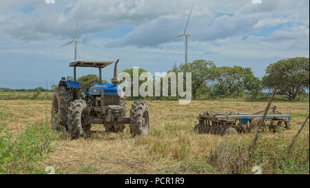 Tracteur agricole et herse à disques après une journée de travail dans un champ avec les éoliennes dans l'arrière-plan Banque D'Images