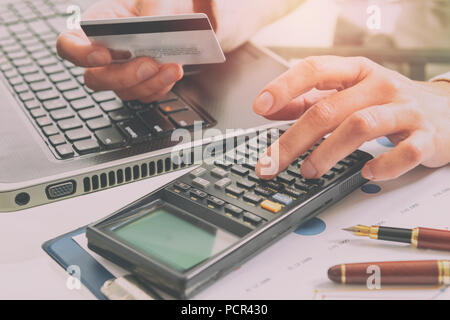 Tenir la main de femme carte de crédit sur le clavier d'ordinateur portable, autre part sur calculatrice Banque D'Images
