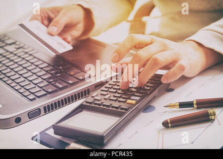 Tenir la main de femme carte de crédit sur le clavier d'ordinateur portable, autre part sur calculatrice Banque D'Images