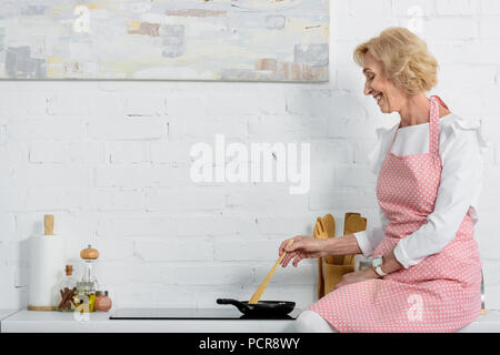 Happy senior woman in apron cooking in kitchen Banque D'Images