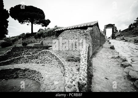 Rue pavée menant à une sorte de porte vers le centre-ville de la ville antique de Pompéi, près de Naples, Italie Banque D'Images