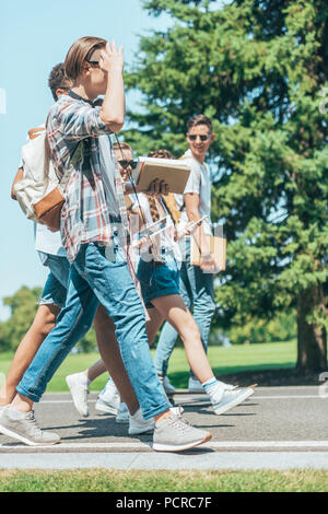 Vue latérale d'étudiants adolescents avec des livres de cuisine walking together in park Banque D'Images