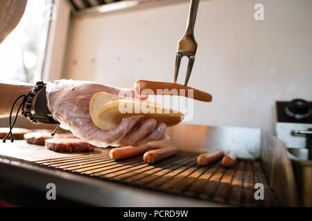 Portrait du chef préparer hod dog en camion alimentaire et l'ajout de sausage Banque D'Images