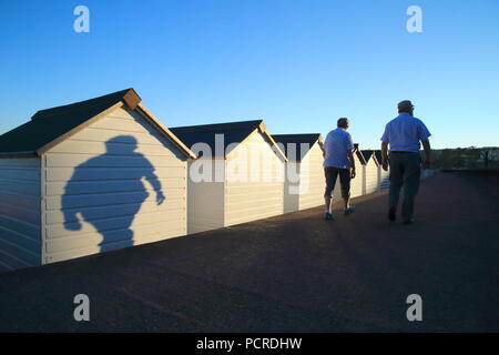 Les ombres des gens passant par White Beach huts dans ville côtière de Seaton dans l'est du Devon Banque D'Images