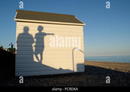 Les ombres des gens passant par White Beach huts dans ville côtière de Seaton dans l'est du Devon Banque D'Images