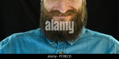 Portrait of Smiling Barbu dans une chemise en denim bleu sur fond noir. Look Hipster : barbe et moustache Close-up Banque D'Images