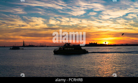 Bateaux en passant par la rivière Hudson à la recherche sur un beau coucher de soleil d'hiver sur l'île ellis et toujours présent il Statue de la liberté, NEW YORK, USA Banque D'Images