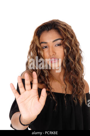Un sérieux à la jeune femme d'un haut noir et long cheveux bouclés brunette holding sa part de la défense, de l'isolé pour fond blanc Banque D'Images
