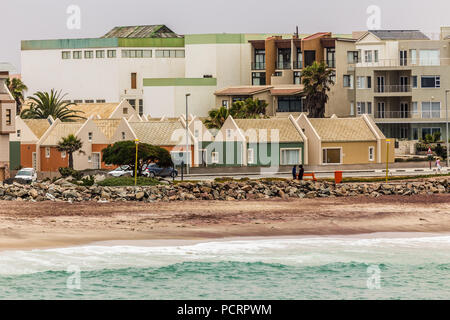 Les vagues et le littoral avec des maisons colorées et des appartements, ville coloniale Allemande de Swakopmund, Namibie Banque D'Images